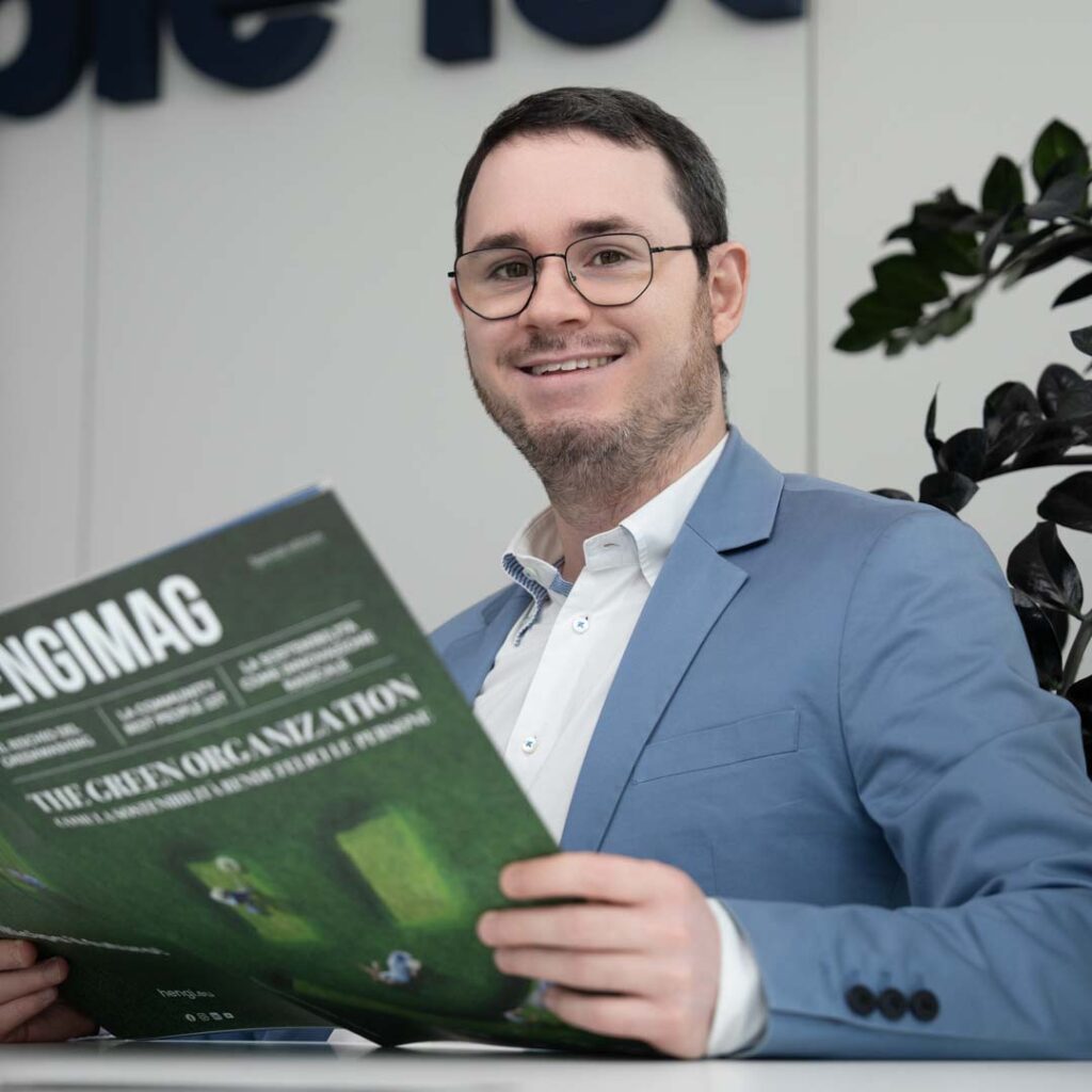 Ragazzo con in mano un magazine verde e di sfondo una parete bianca